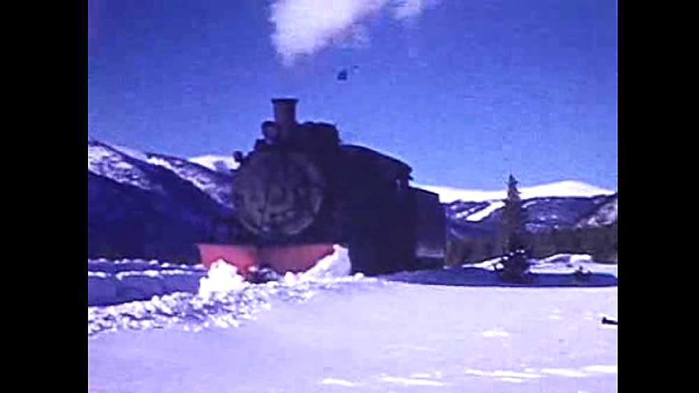 Steam locomotive with red snowplow in snow