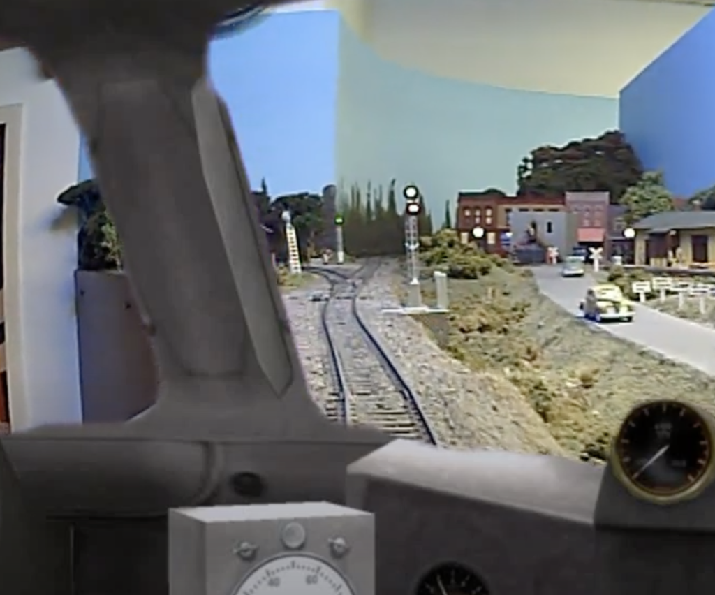 View of a model train layout as seen from a camera looking through a "cab window."