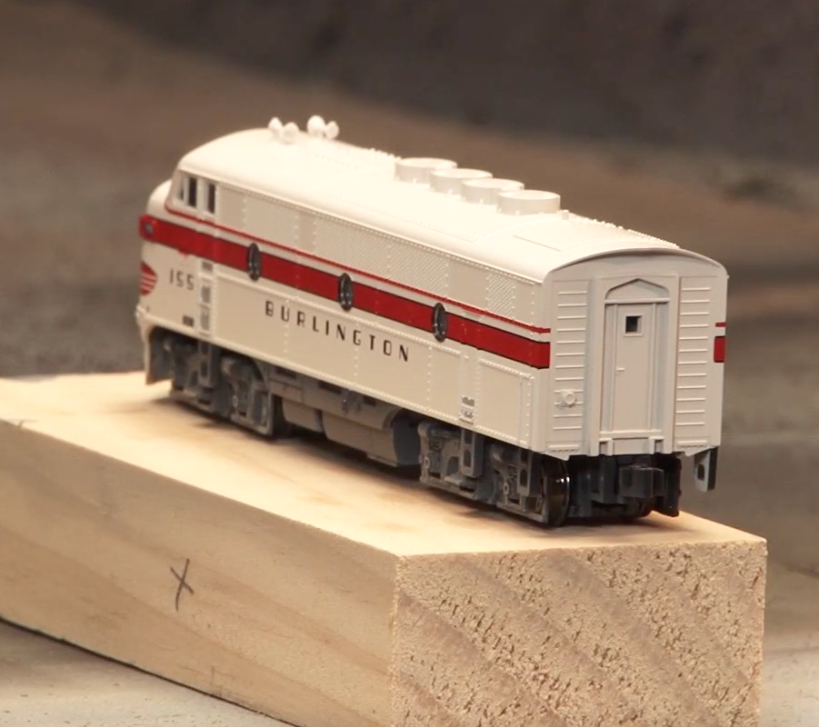 White painted cab-unit style diesel locomotive sitting on a wood block.