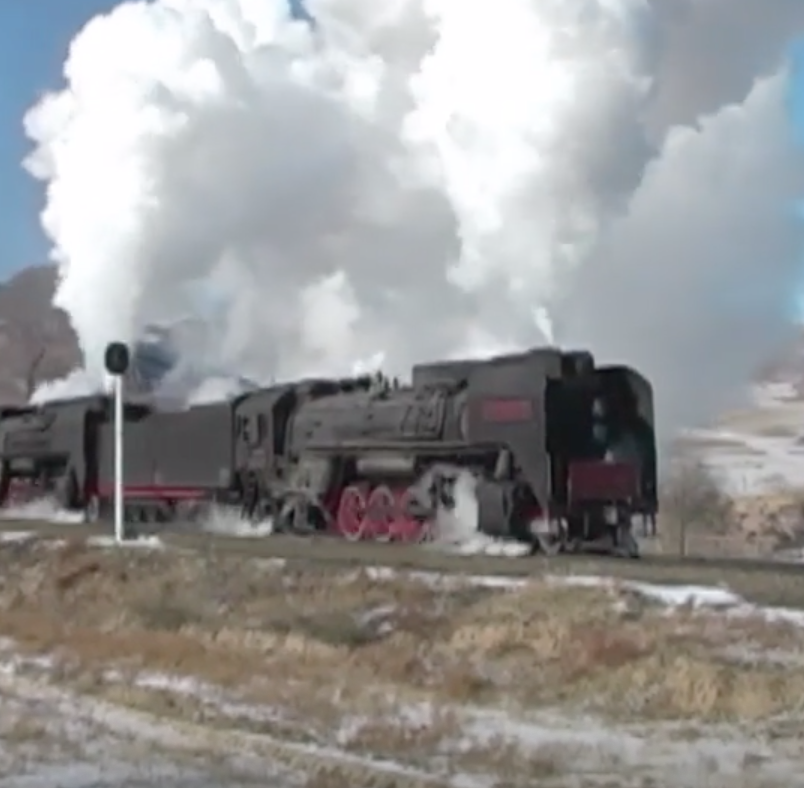 Steam locomotive with large white plumes.