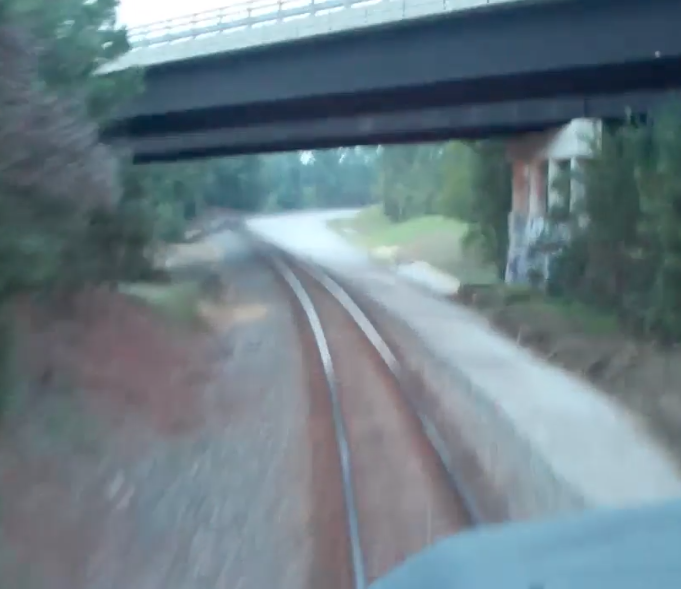 View from a locomotive cab at bridge overpasses and railroad track.
