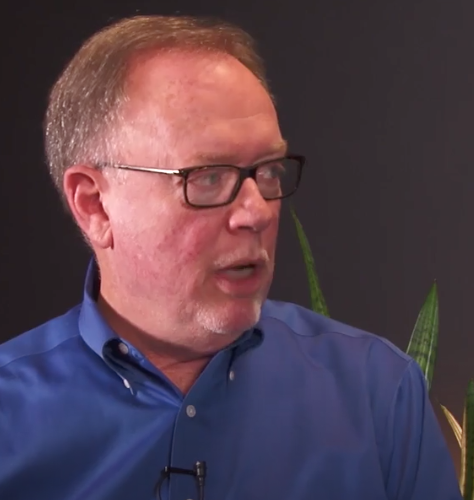 Man wearing blue shirt and glasses, speaking.