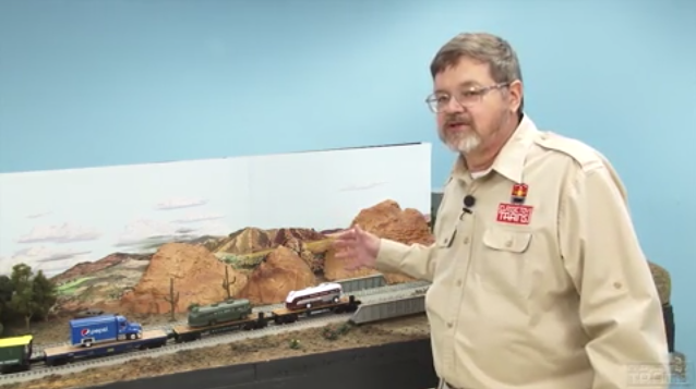 Bob Keller standing next to a model railroad layout