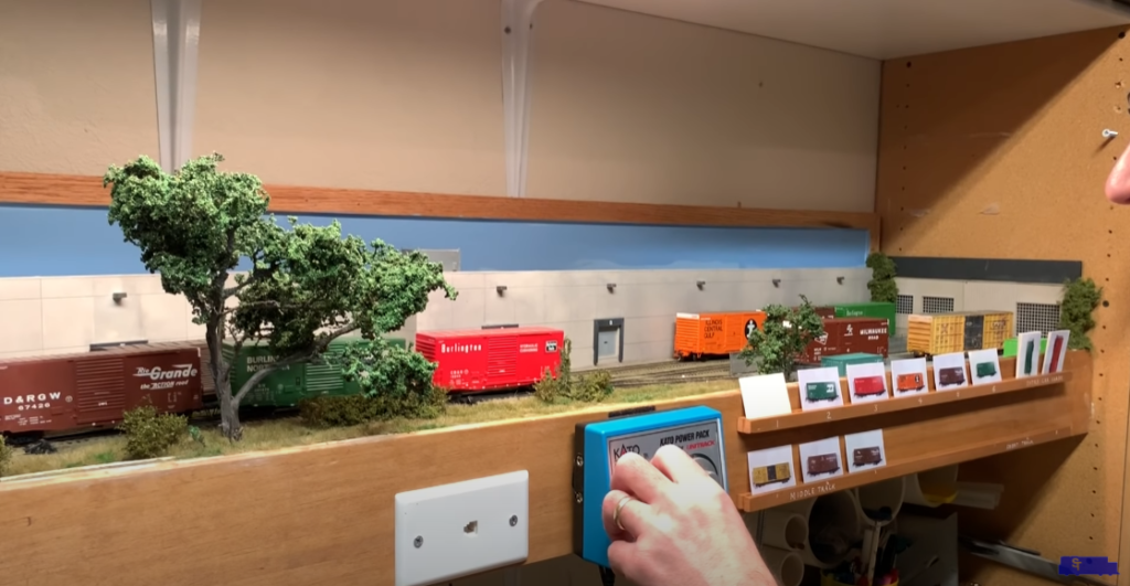 Hand operating a switching model train layout