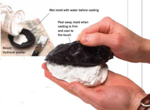 Hands casting a plaster rock