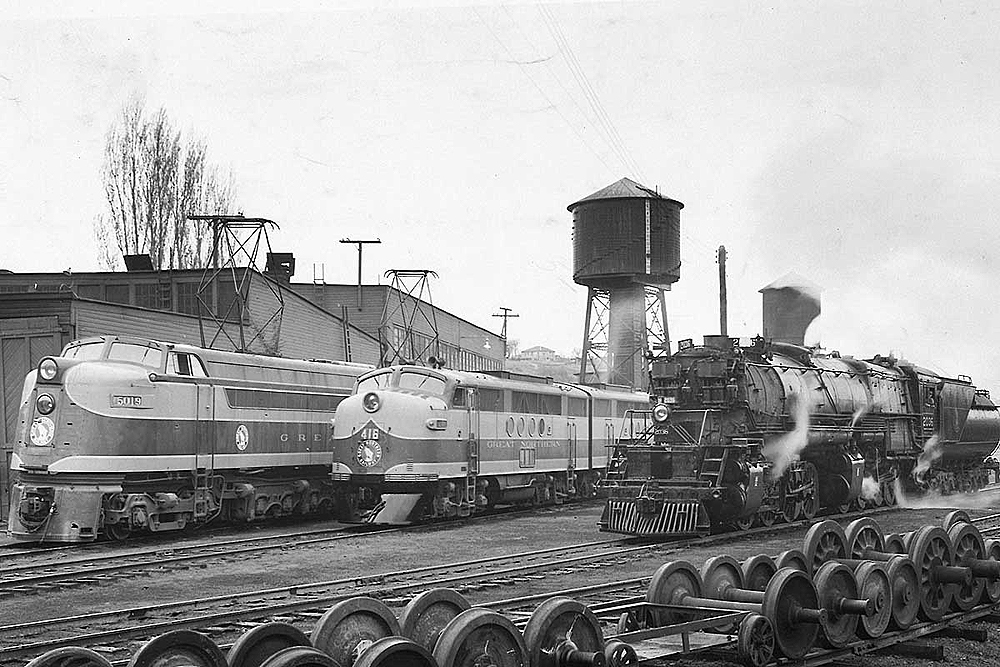 A black and white photo of a steam locomotive and a couple of diesel locomotives