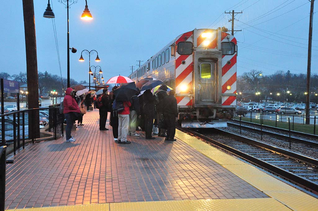 Passengers waiting in the rain to board the metra