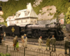 A 4-6-2 steam locomotive model pulls a train through the center of a town in a mountainous and forested scene.