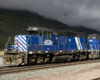 A blue and white train passing by on a stormy day