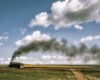 Smoking steam locomotive with yellow passenger train