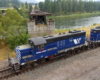 An overhead shot of a blue and white train passing by some water