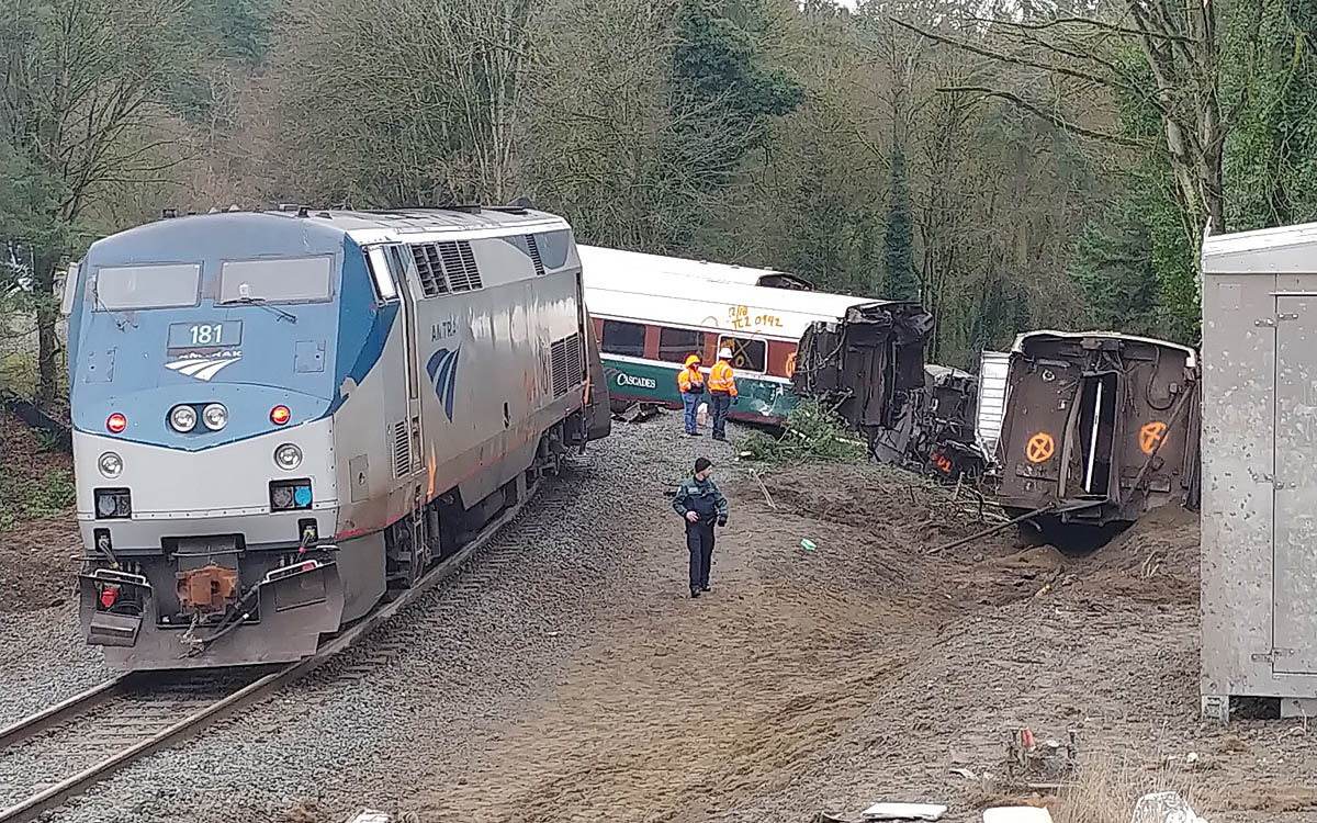 Locomotive stopped on tracks with derailed cars in background