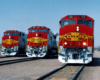 Three red and yellow santa fe trains sitting on the tracks