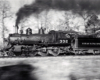 A locomotive fastly moving by with black smoke coming out of its chimney