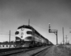A black and white photo of locomotive F7A 1513 on the tracks passing a stop light