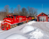 A red train passing by a snowy depot