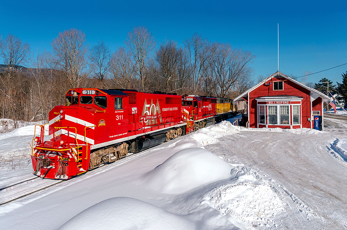 A red train passing by a snowy depot