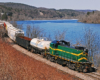 A train turning a corner next to a body of water