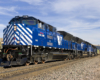 A blue train passing through a rural area