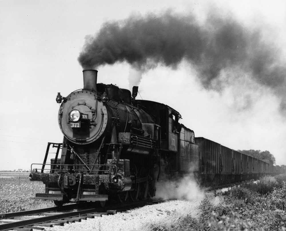 A black and white photo of Pere Marquette 2-8-0 No. 371 with black smoke coming out of its chimney