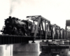 A black and white photo of Mikado 1097 moving over a bridge