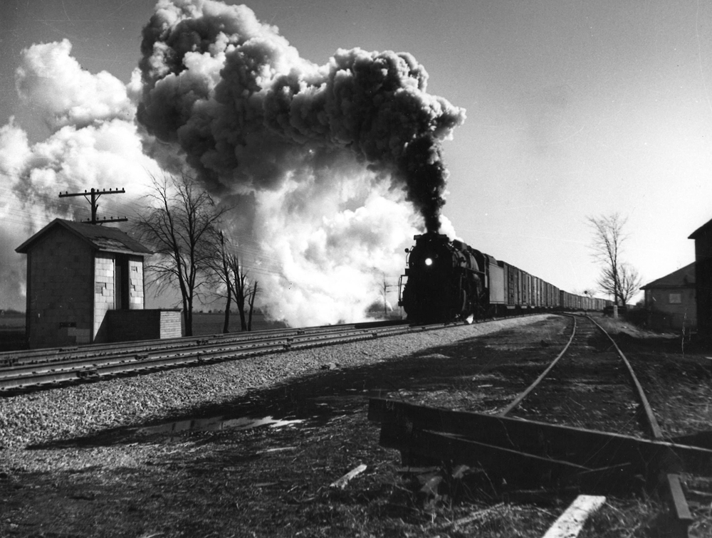 A black and white picture of Berkshire 1220 with its headlight on and smoke coming our of its chimney.