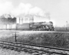 A black and white photo of Pere Marquette on the tracks with white smoke coming out of its chimney. Another set of tracks is right next to it.