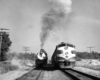 A black and white photo of two locomotives side by side on the tracks 