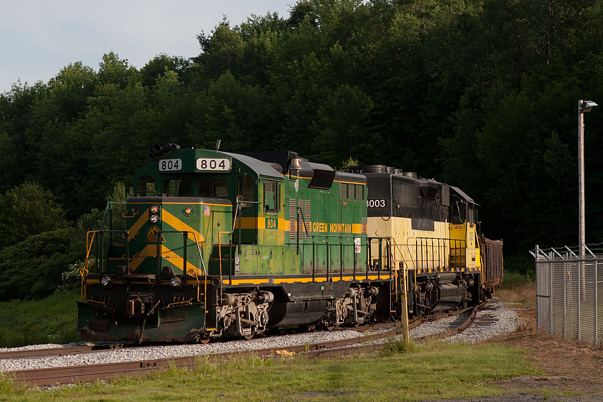 A train turning a corner surrounded by trees