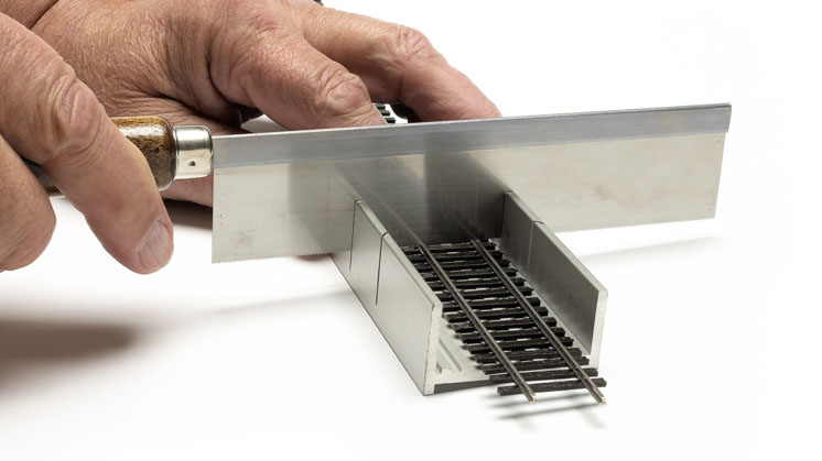 How to cut and fit sectional and flextrack: A fine-tooth razor saw cuts a section of model rail track.