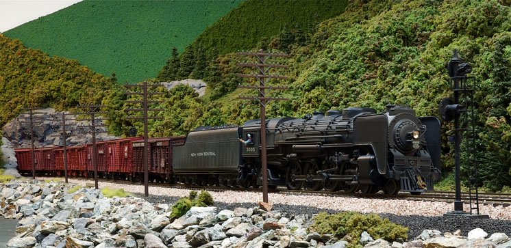 A 4-8-2 steam locomotive leads a stock car train passed several large telephone-telegraph poles.