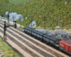 Three matching black-and-grey locomotives haul a train on a multi-track mainline in a verdant, mountainous scene.