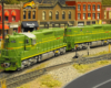 Two model green diesel-electric locomotives in an urban scene.