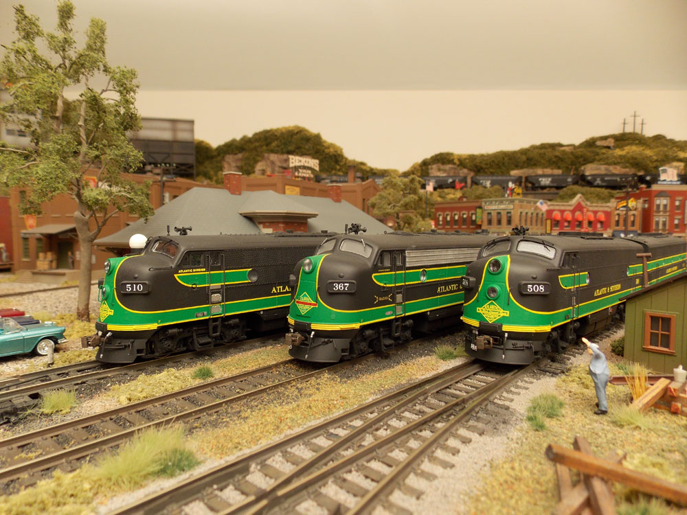 Three black and green cab-unit style diesel-electric locomotives side by side.