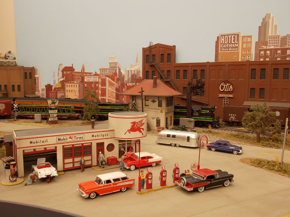 Green and black diesel-electric locomotives haul a freight train in a brickwork industrial scene.