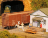 Close-up view of figures and horse near a freight station and a boxcar on a track.