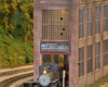 A steam locomotive pokes out of the corner railroad entrance of a multi-story brick building.