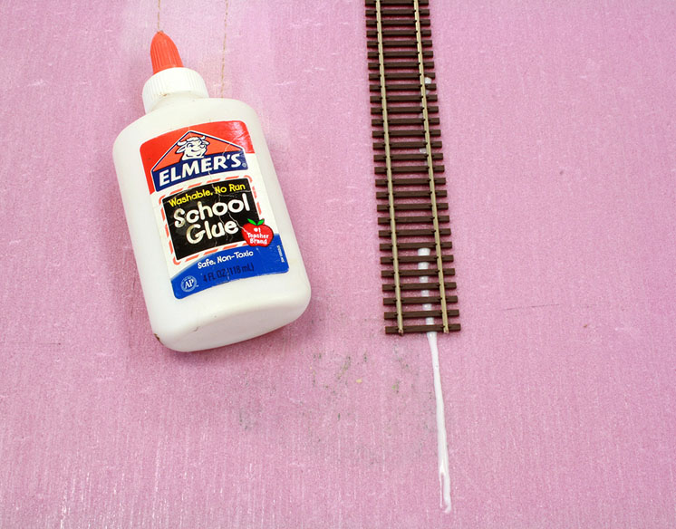 An image of Elmers glue next to track applied to foam board.