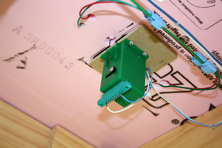 An image of a switch motor on the underside of a foamboard layout.