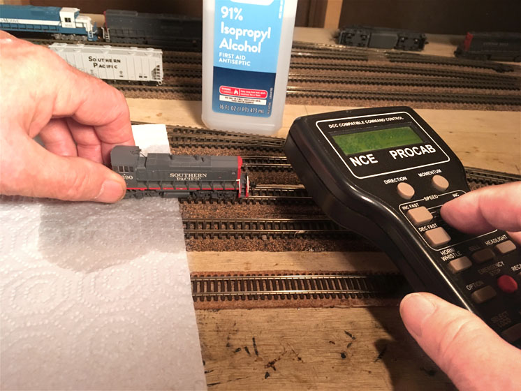 Dirt and N scale layout: A model locomotive being run on model railroad track with a controller next to it