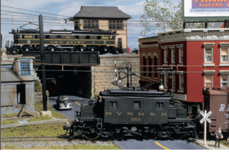 Model electric locomotives in an older urban scene.