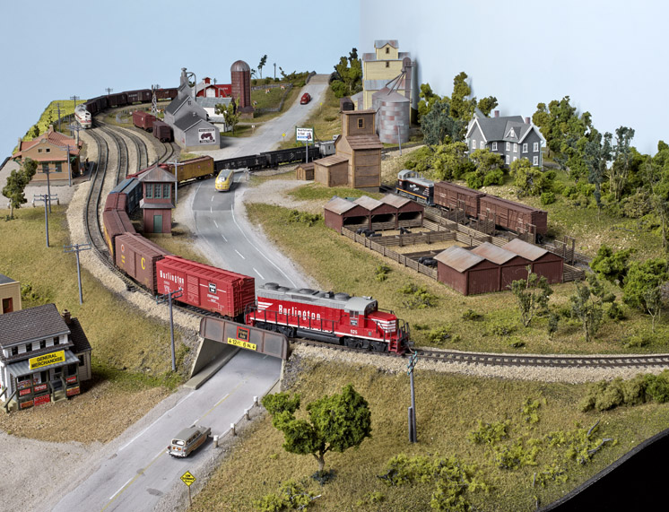 an HO scale layout with a red diesel pulling boxcars