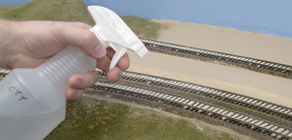An image of a spray bottle above a model railroad layout.