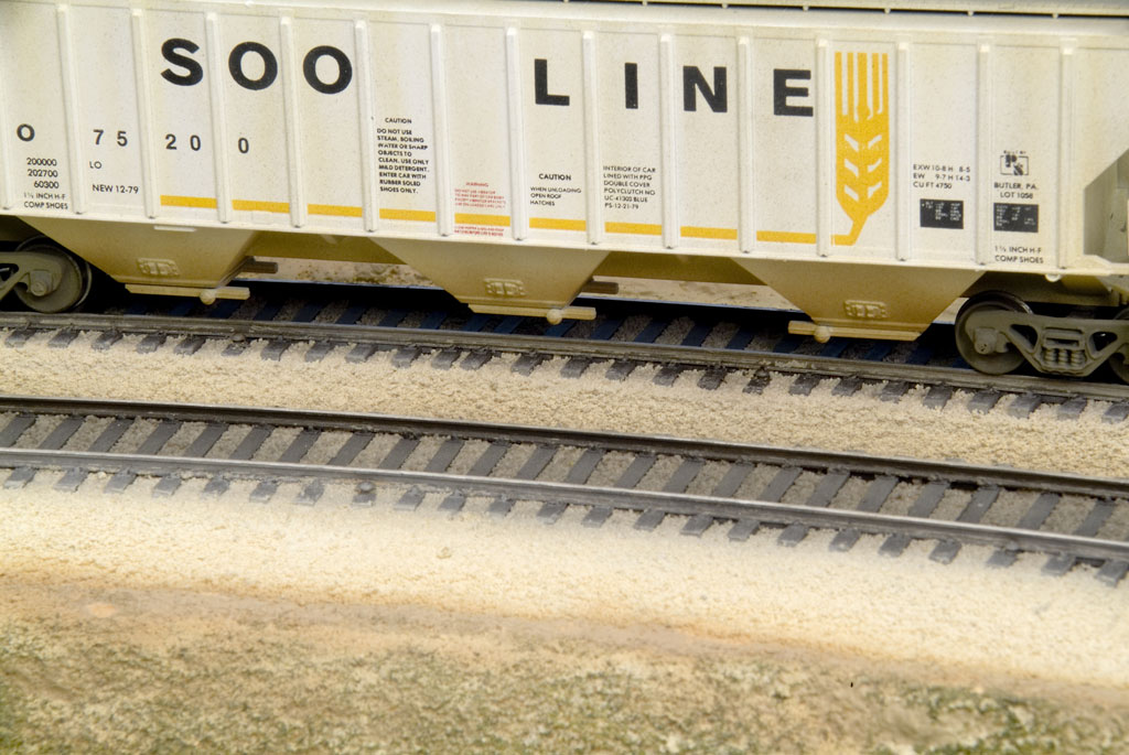 An image of a cream colored model hopper car on track