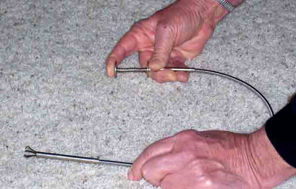 hands holding a metal grabber tool