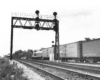 A black and white photo taken from behind a GP7 diesel locomotive as it passes by a stop light