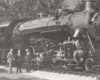 a steam engine with three people standing in front of it
