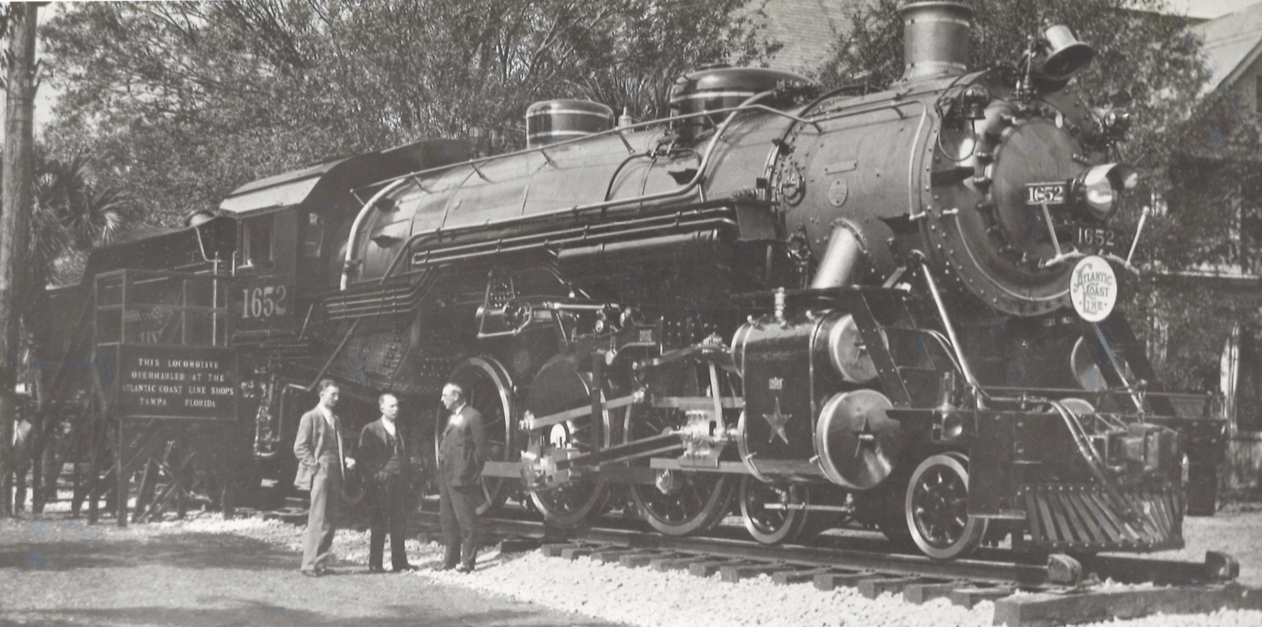 a steam engine with three people standing in front of it