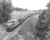 A black and white photo of a diesel locomotive moving through the trees