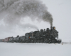 A train plowing through the snow with smoke coming out of its chimney